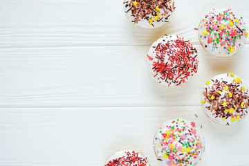 Cupcakes with white cream  and sprinkles on white background