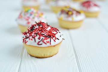 Cupcakes with white cream  and sprinkles on white background