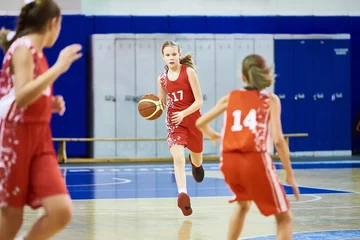 Fotobehang Girls athlete in sport uniform playing basketball © Sergey Ryzhov