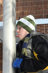Boy sticking his tongue on a flag pole