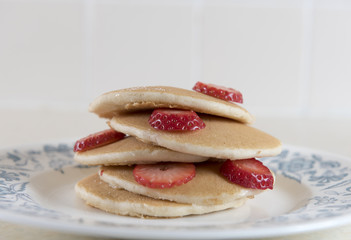 Large stack of golden pancakes covered in strawberries. 