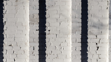 White brick wall with two columns in the middle, with a long shadow, clean white architectural background, white horizontal brick texture 16: 9