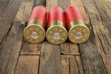 12 gauge red hunting cartridges for shotgun on wooden background. Macro shot.