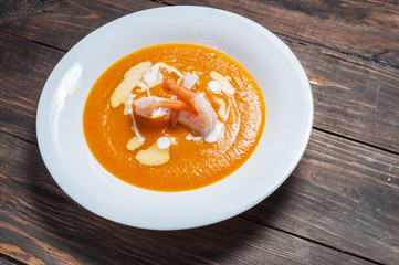 Pumpkin soup with shrimp on a wood