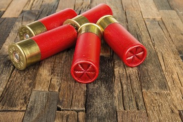 12 gauge red hunting cartridges for shotgun on wooden background. Macro shot.