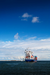 Naklejka premium Cargo ship just leaving Gdynia harbour. Vertical frame. Poland.