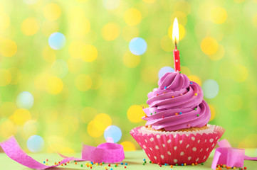 Tasty cupcake with candles on lights background