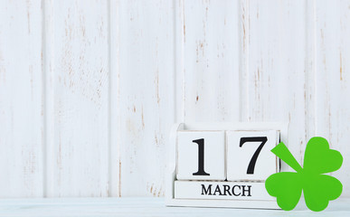 Green paper clover leaf and calendar on wall paneling background