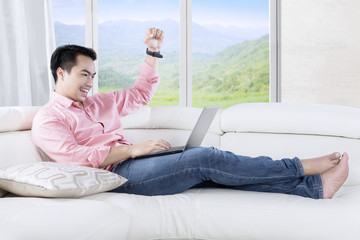 Obraz premium Handsome man uses laptop on couch