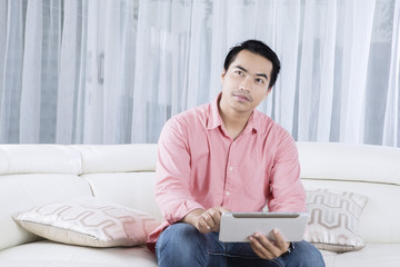Obraz premium Handsome man using tablet on couch