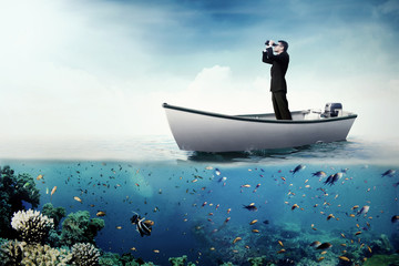 Male worker using binoculars on boat