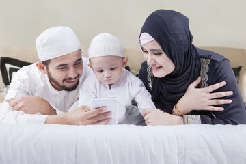Muslim family lying on bed with smartphone