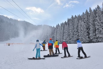 Group of snowboarders resting on the snow while listening to the instructor