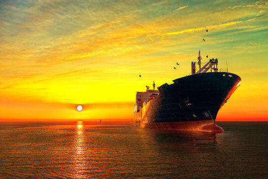 Oil tanker ship at sea on a background of sunset sky.