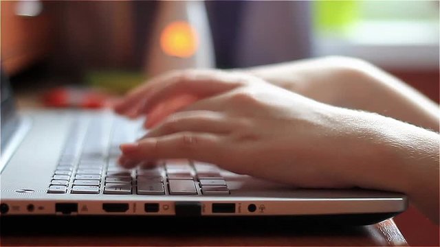 hands of a young woman. using laptop, typing text.