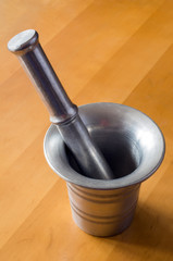 Metal mortar and pestle on wooden background texture.