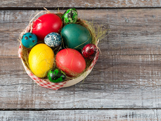 Colorful easter eggs in straw nest on a wooden table