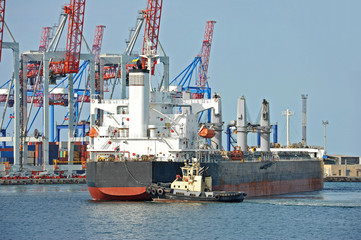 Naklejka premium Tugboat assisting bulk cargo ship