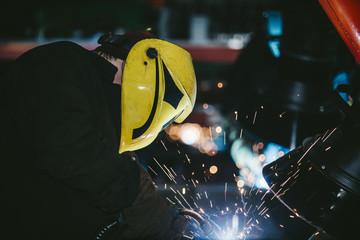 Worker at the factory in the helmet is of iron in the welding pr