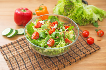 Salad of fresh vegetables and green on wooden background. Healthy food.