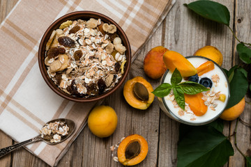 Yogurt with peach in a glass and muesli  on wooden background. Diet breakfast
