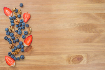 Fototapeta premium Strawberries, blueberries and nuts on wooden background.