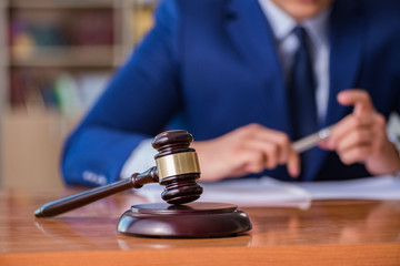 Handsome judge with gavel sitting in courtroom