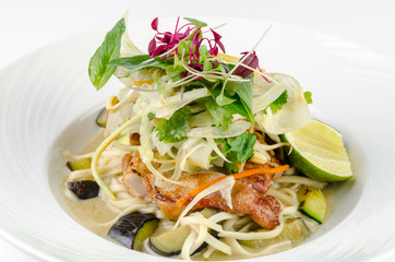 Fillet of sea bass with roasted eggplant and olives on a plate on a white background, closeup
