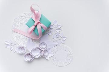 a gift on a white napkin and white paper flowers