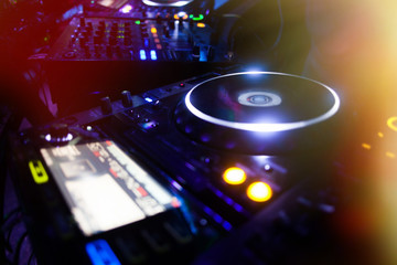 Obraz na płótnie Canvas DJ playing music at mixer closeup and mixes the track in the nig