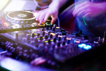 Obraz premium DJ playing music at mixer closeup and mixes the track in the nightclub at party