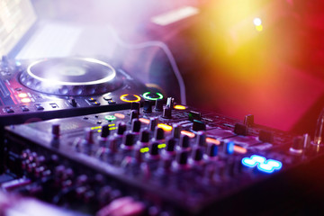 DJ playing music at mixer closeup and mixes the track in the nig