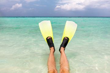 Snorkeling in the ocean. Fins on legs in clear water, Maldives.