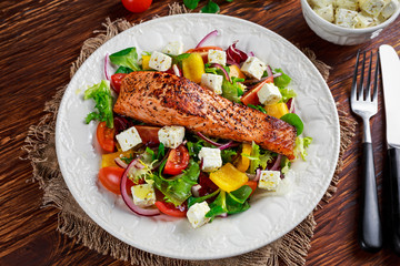 Fried Salmon steak with fresh vegetables salad, feta cheese. concept healthy food.