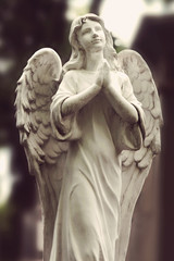 Vintage image of a sad angel on a cemetery against the backgroun