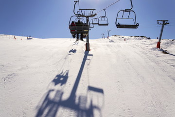 People on ski chair lift in sunny winter Alps, Austria