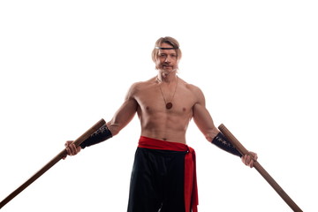 Actor Athlete man in trousers with naked torso practicing with wooden swords on a white background