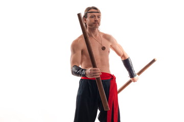 Actor Athlete man in trousers with naked torso practicing with wooden swords on a white background