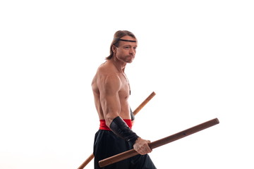 Actor Athlete man in trousers with naked torso practicing with wooden swords on a white background