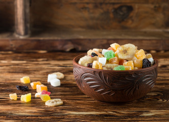 Candied and dried fruits in a bowl on a wooden table. A rustic style. Selective focus
