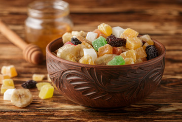 Candied and dried fruits in a bowl on a wooden table. A rustic style. Selective focus
