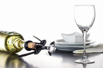 Korkenzieher mit Naturkorken vor Weinflasche, Glas und Geschirr