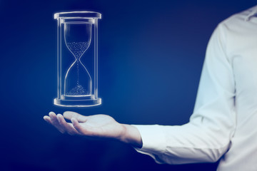 Man's hand holding hourglass sand