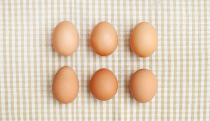 Six chicken eggs and wooden spoon on fabric on top shot 