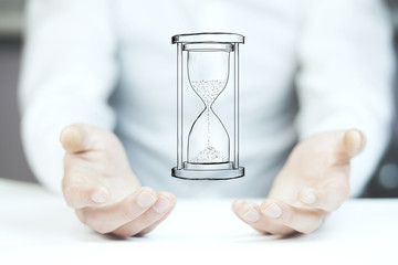 Man's hand holding hourglass sand