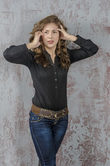Fototapeta premium Young girl with curly hair in a black shirt, jeans and high boots cowboy western style 