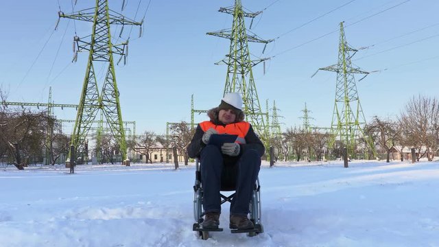 Disabled worker on wheelchair writing under high-voltage lines