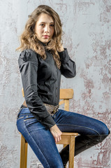 Young girl with curly hair in a black shirt, jeans and high boots cowboy western style
