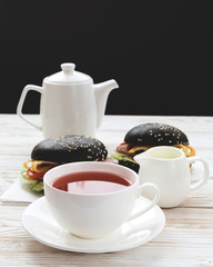 Black Hamburger , cup of tea and milk for breakfast.
