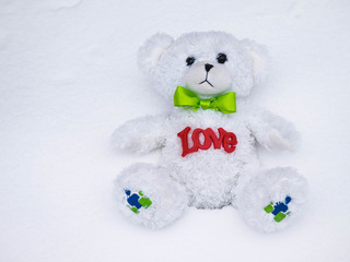 Plush teddy bear sits on the white snow